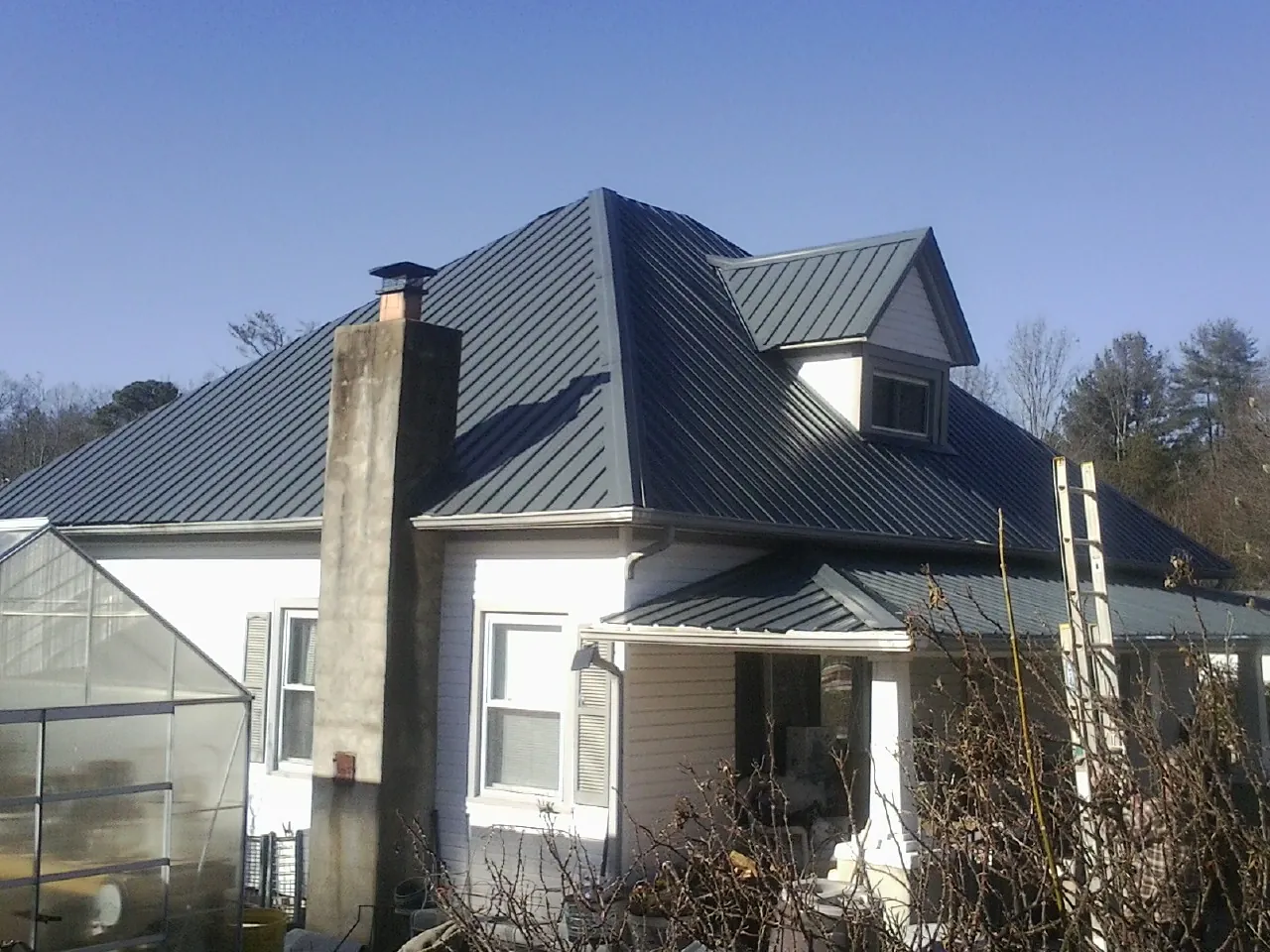 Dark blue standing seam metal roof on a white farmhouse with dormer — Slate & Tile Roof Repair by Roofing Brothers in North Beach