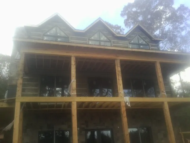 Dormers and porch framing on a large log home under construction — Roof Coating work by our crew in North Beach