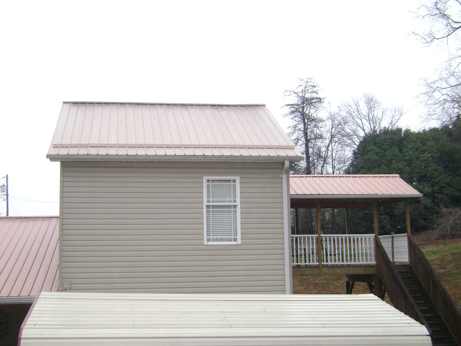 Tan metal roofs on a two story addition and attached porch, from a Roof Replacement job in North Beach