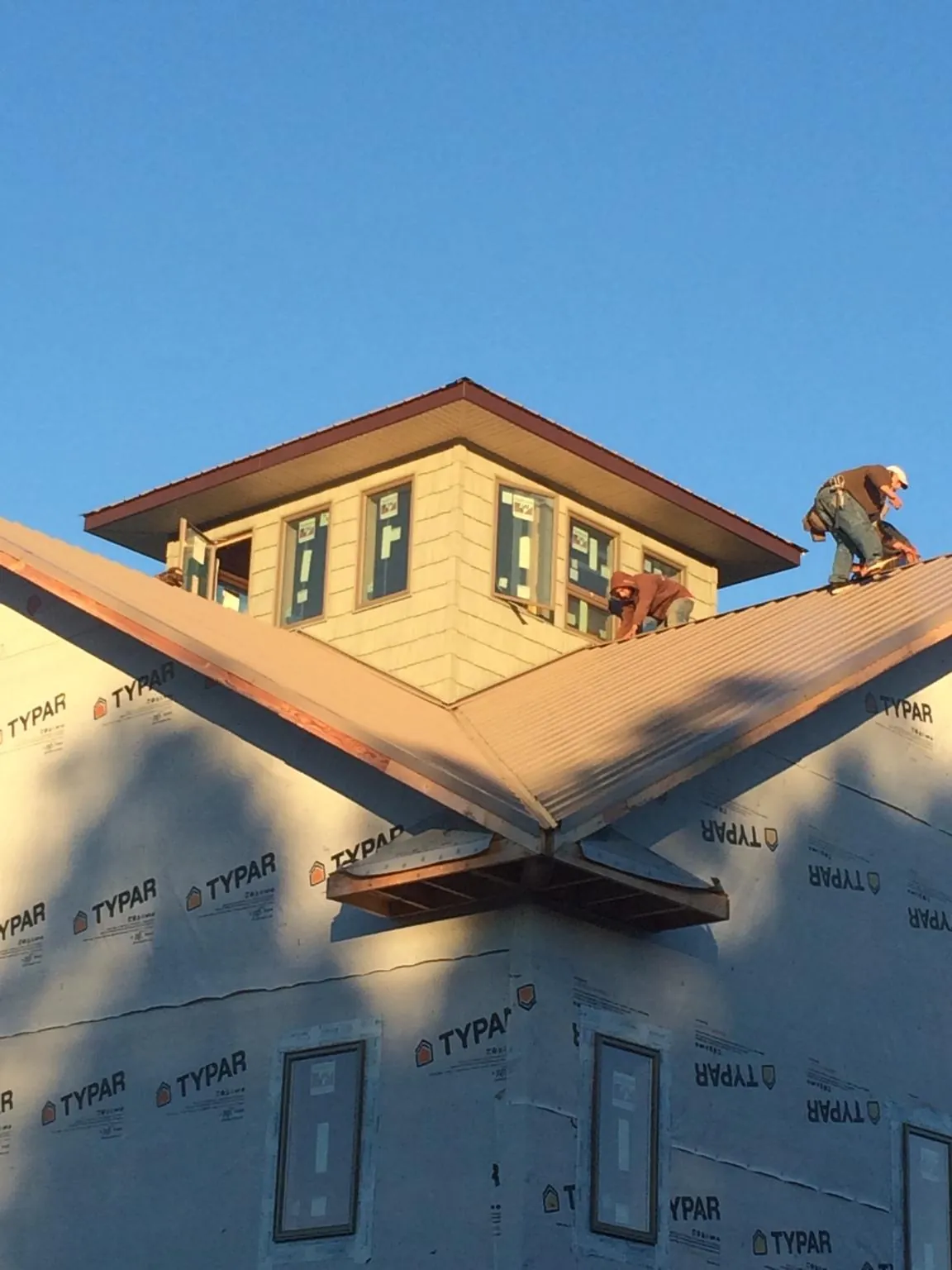 Roofers working around a rooftop cupola on a new metal roof at sunset — Roof Waterproofing in North Beach by Roofing Brothers